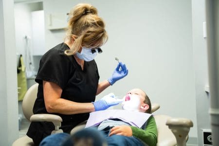 A hygienist cleaning a boy's teeth in the Franklin Smiles dentist office.