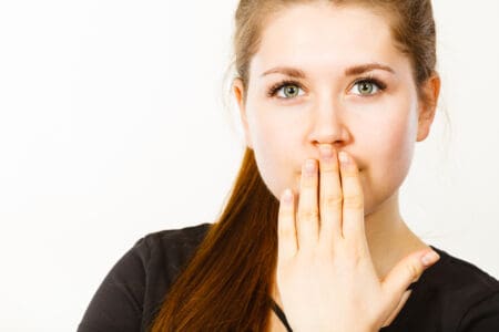 An image of a woman covering her mouth with her hand.